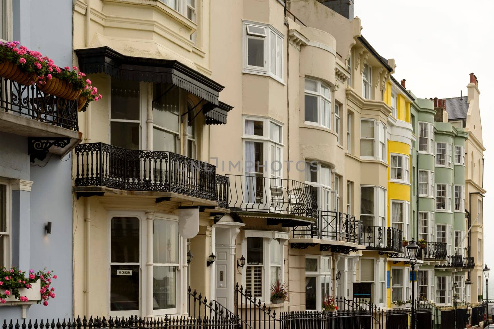 foreshortening of bow windows on facades of old houses on an uphill street in touristic sea town,  Brighton, East Sussex.