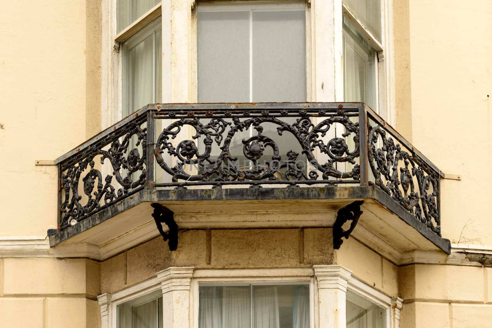 detail of highly decorated balcony railing made in cast-iron  in center of touristic sea town, shot from the public street,  Brighton, East Sussex.