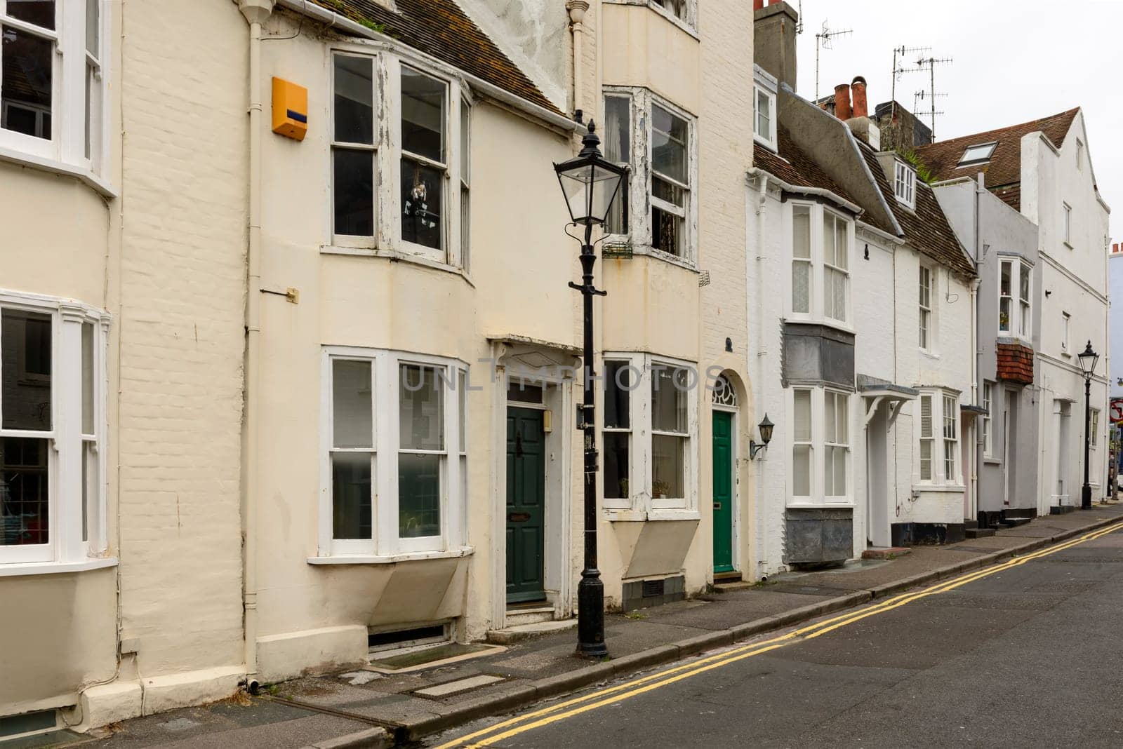 foreshortening of  a lamppost and a row of old cottages on an uphill street in touristic sea town,  Brighton, East Sussex.