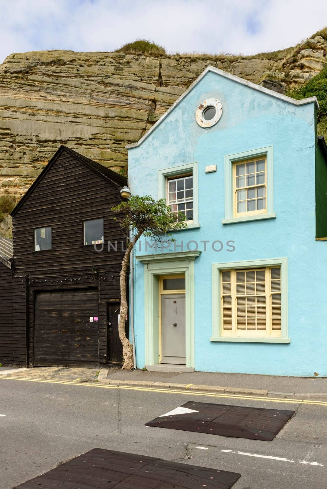 view of old buildings built just under the cliffs in historic touristic village of Hastings, East Sussex.