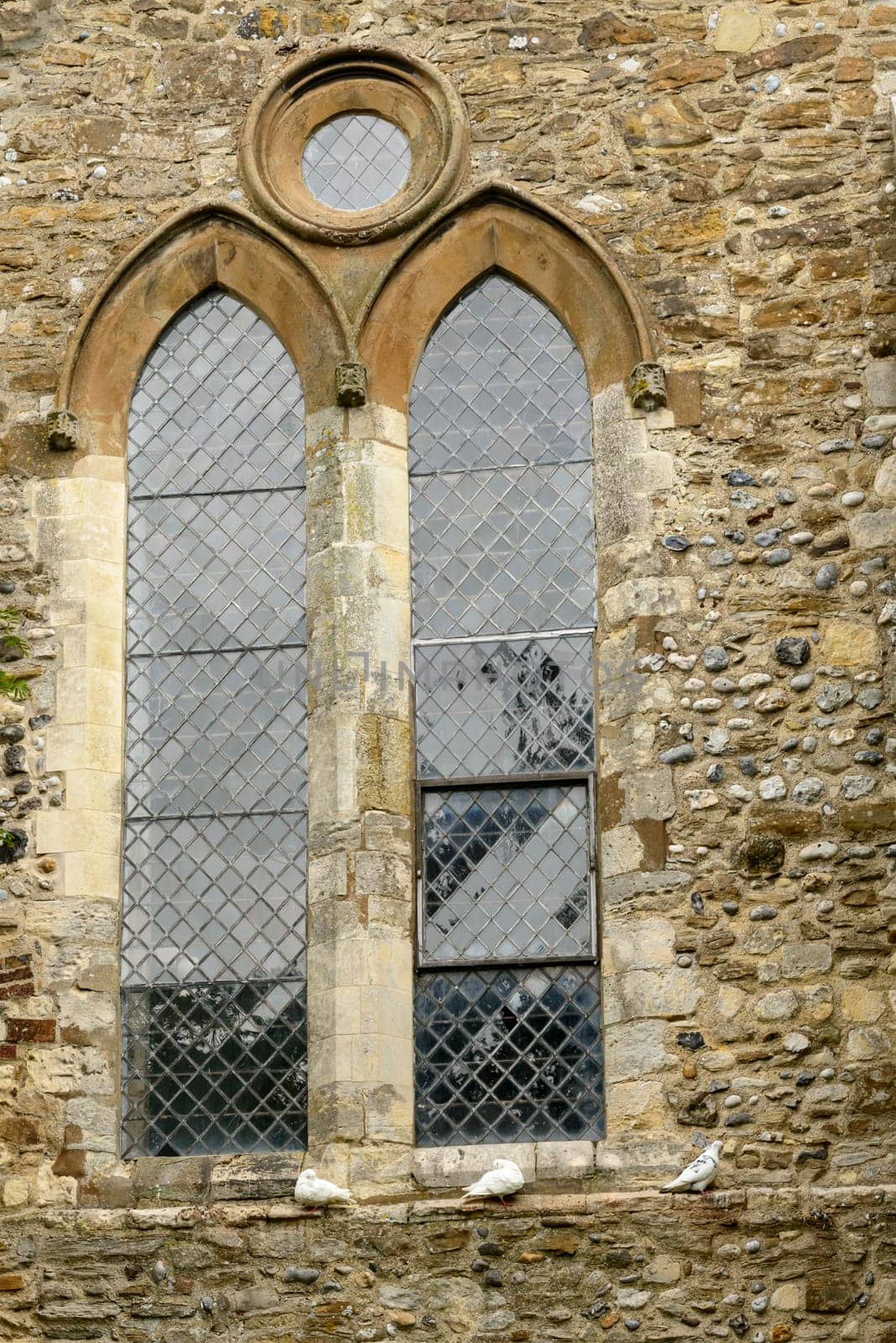 detail of a stained-glass mullioned window of ancient stone church  in small  historic village of Rye, East Sussex ..