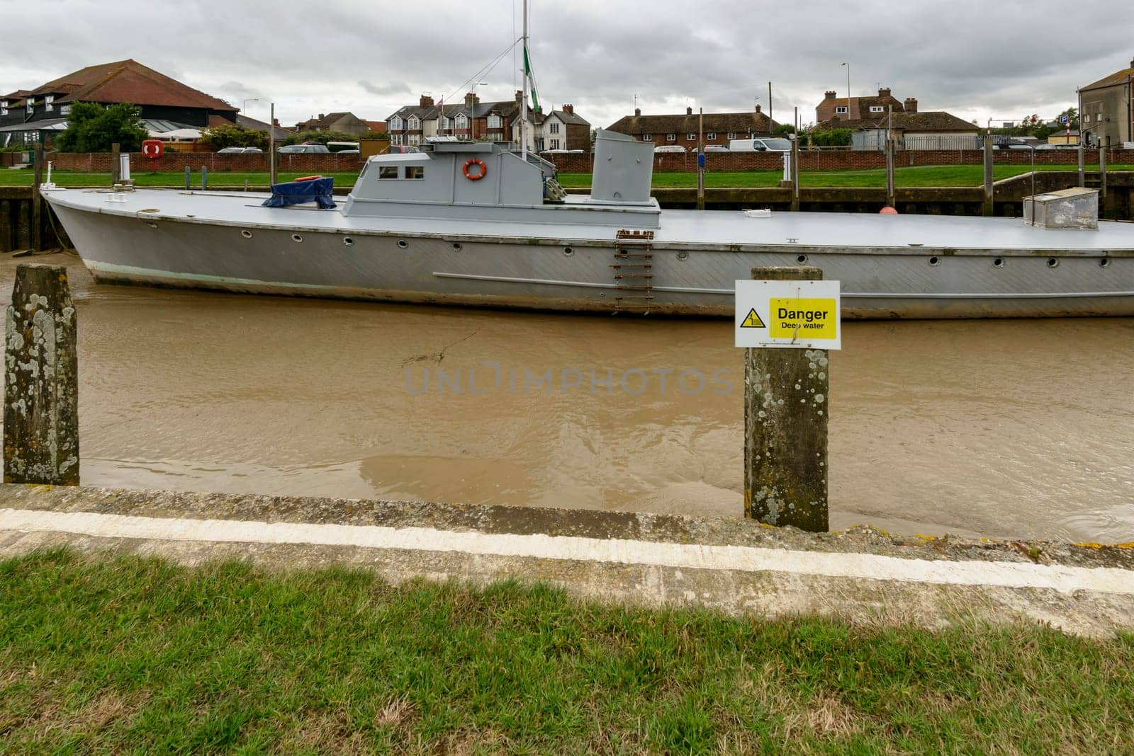 view of a large boat aground at low tide at embankment of river harbor at the historic village of Rye, East Sussex .