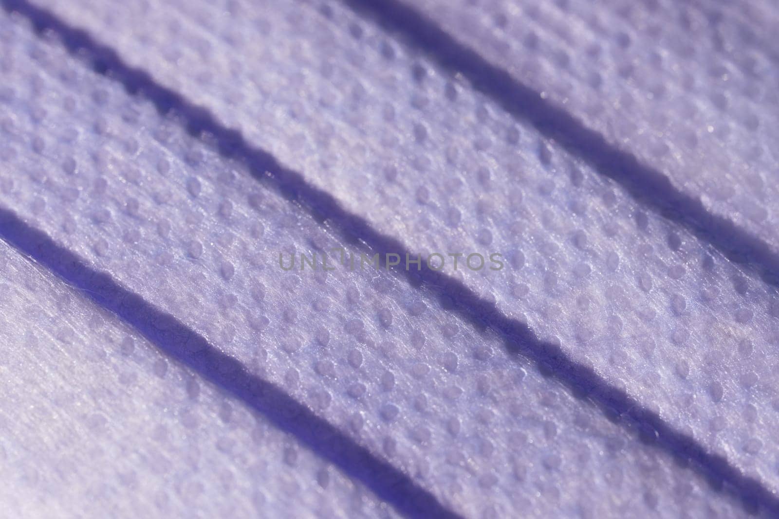 Super macro image showing the surface texture of a 3 ply single use face mask. Medical mask with 3 folds, splash proof and filtering ability.