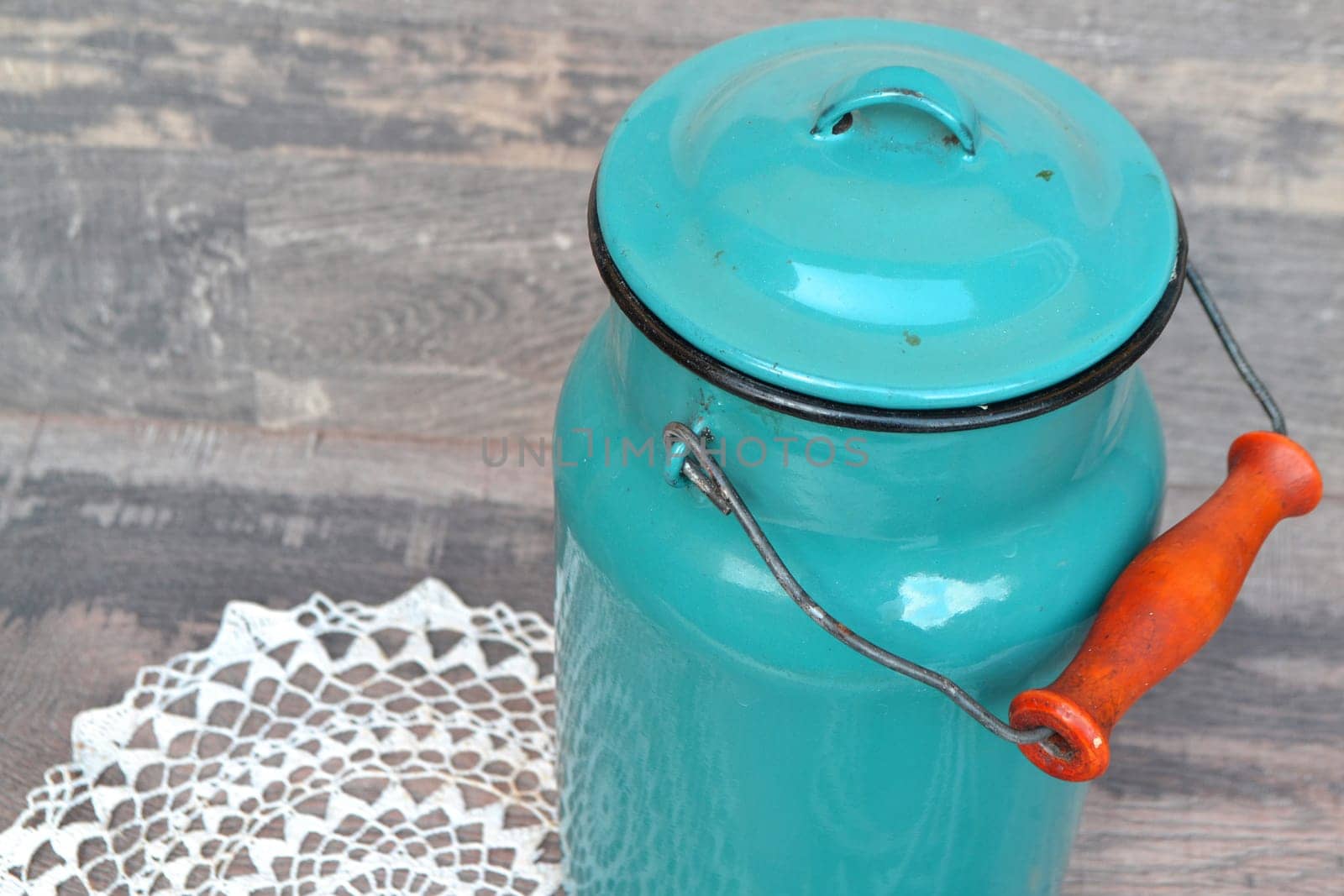 Old blue milk can onwooden background in vintage style close up
