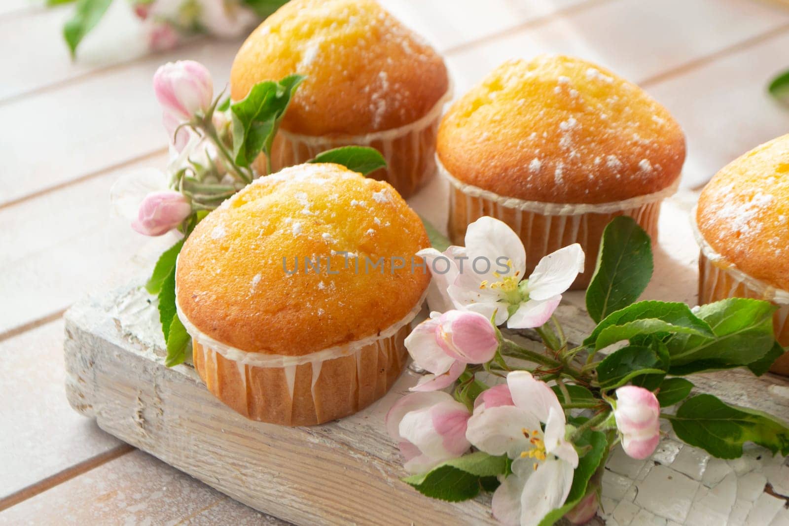 Muffins and spring flowers on a wooden shabby table
