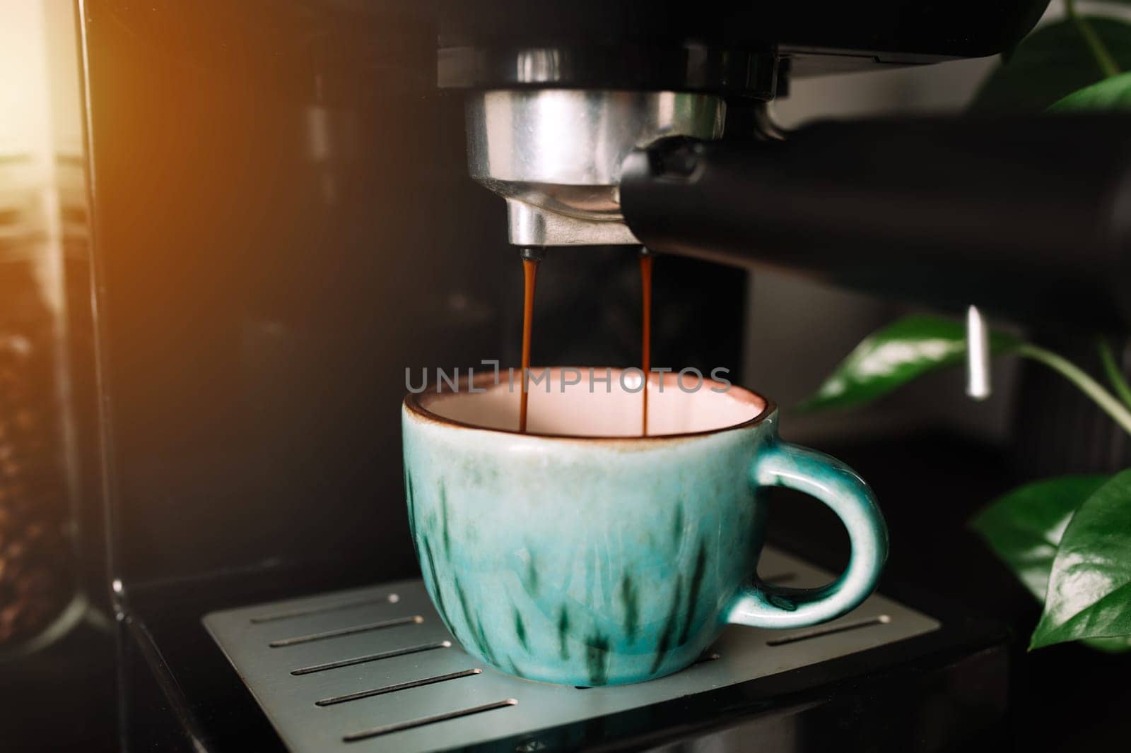 Green cup of coffee at the coffee maker machine, coffee time. Blurred background. High quality photo