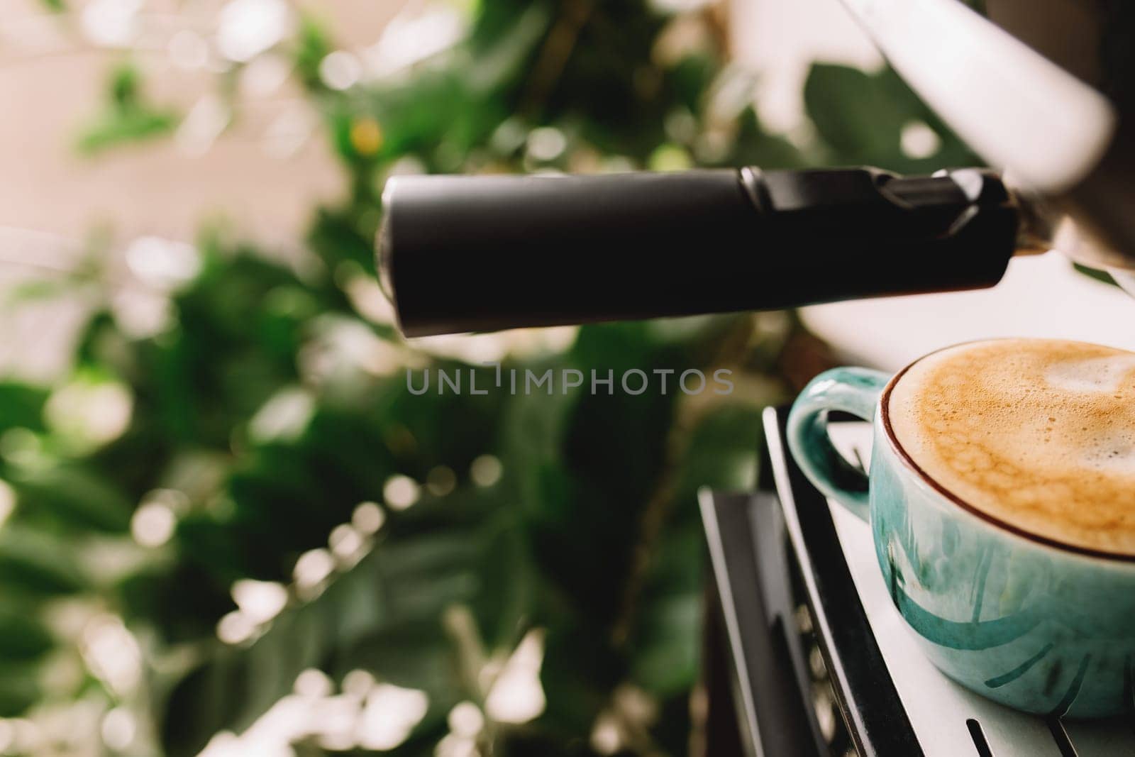 Green cup of coffee at the coffee maker machine, coffee time. Blurred background. High quality photo