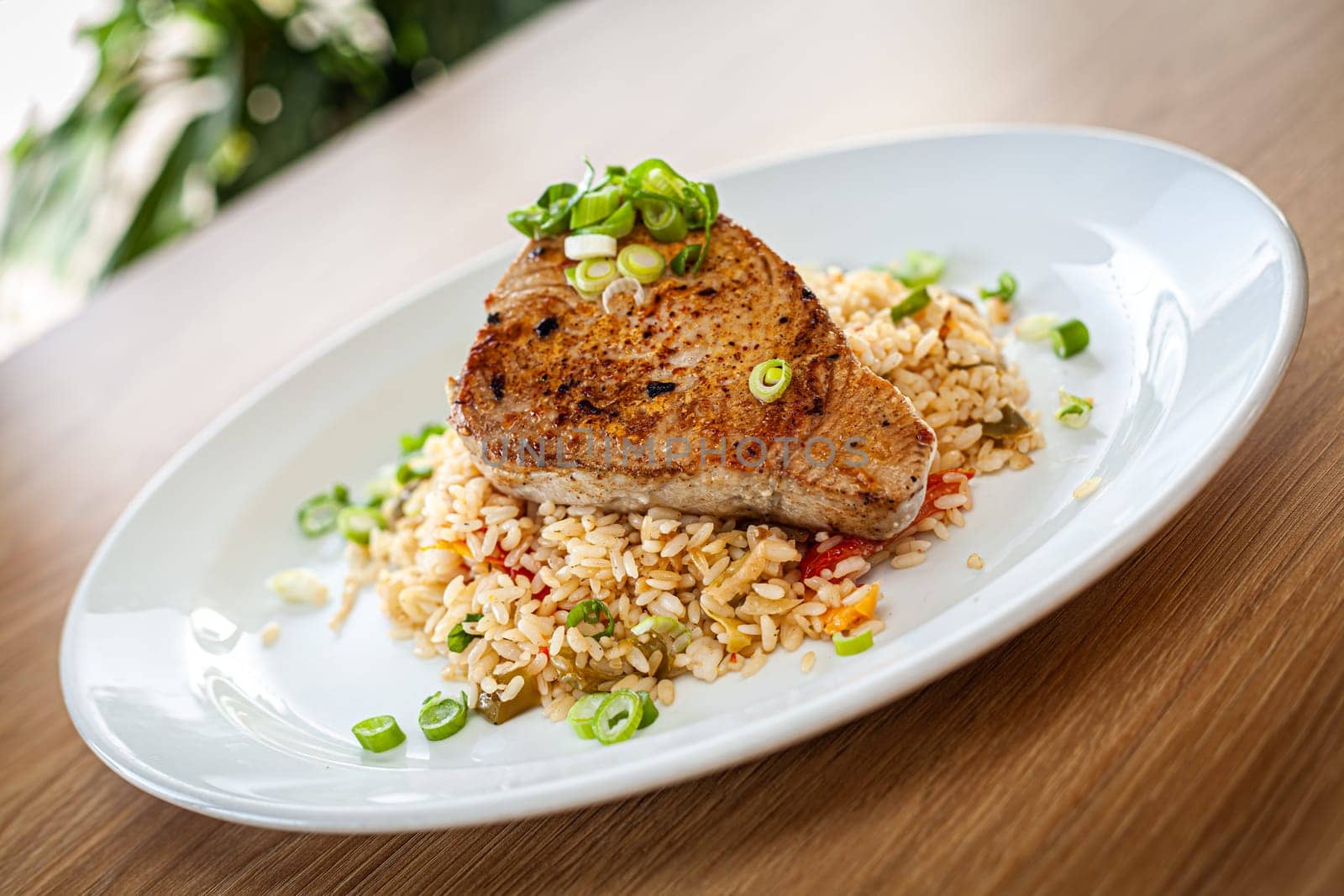 Cooked food on a white plate - tuna served on vegetable risotto.