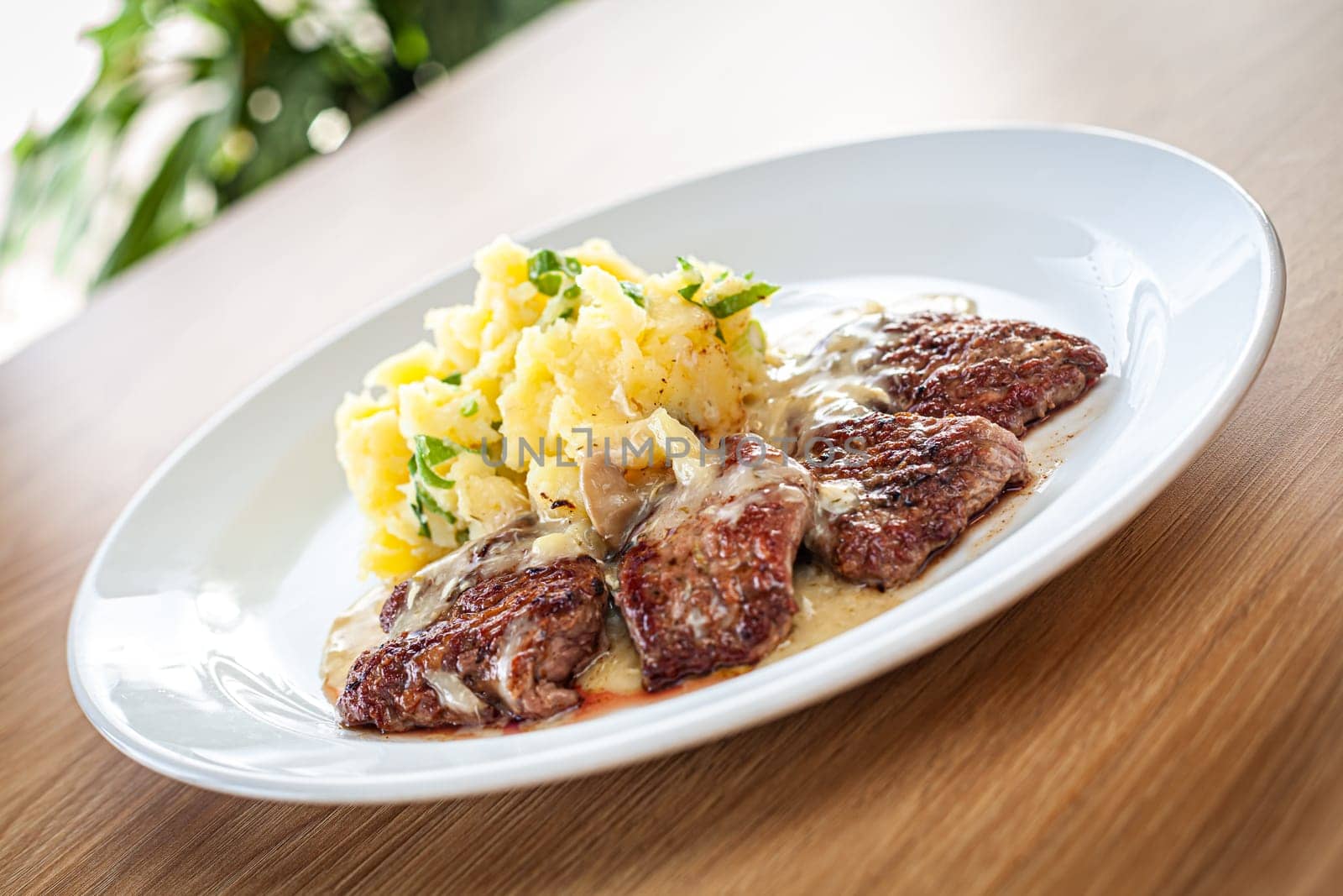 Cooked food on a white plate - pork tenderloin with bra, pine nuts and spring onions.