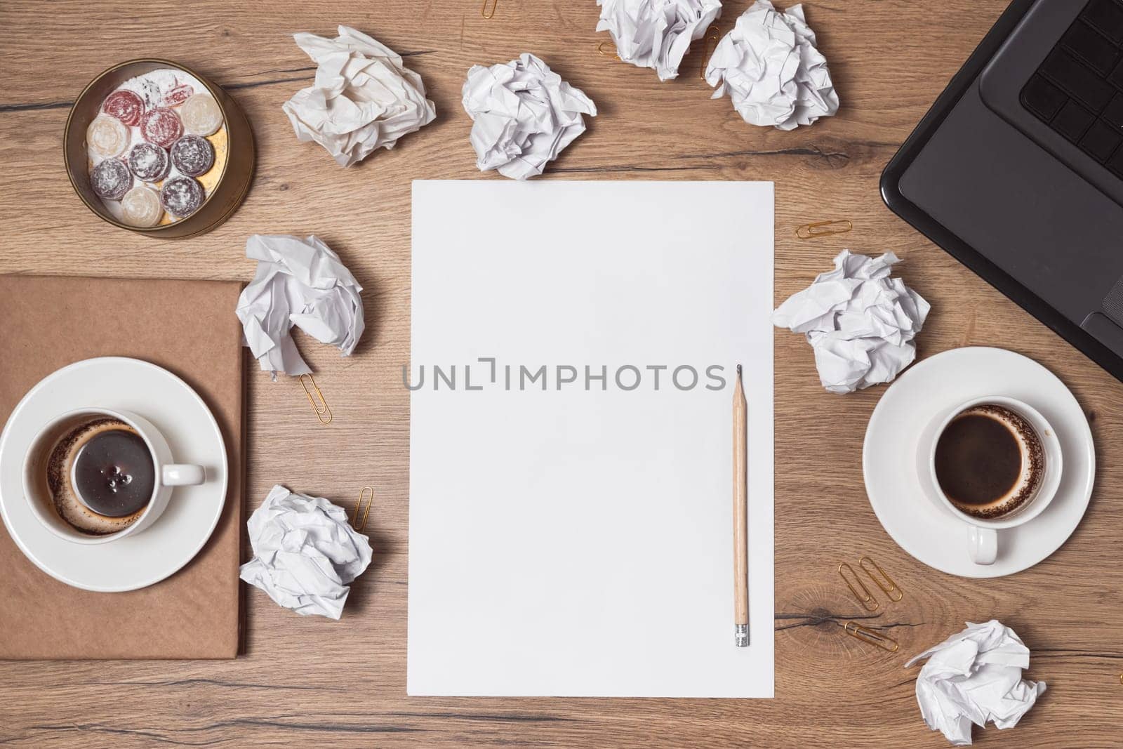 Crumpled papers scattered, empty cups of coffee on table of a creative worker. Creative crisis. Concept of stress, mental health trouble and lack of ideas.