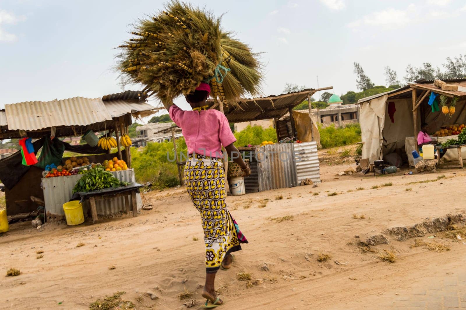 African woman carrying a bundle on her head in a small market near Watamu in Kenya