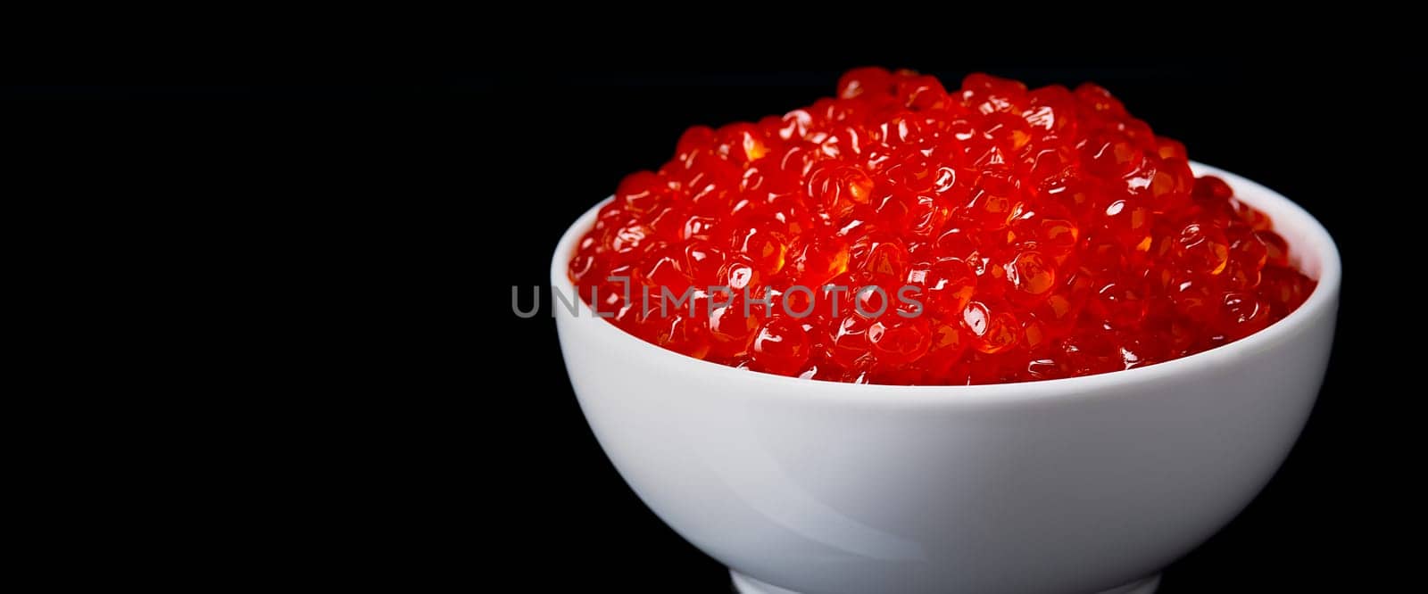 Red caviar in a white cup on a black background with a reflection. Place for advertisement, logo, label, mockup, mock-up.