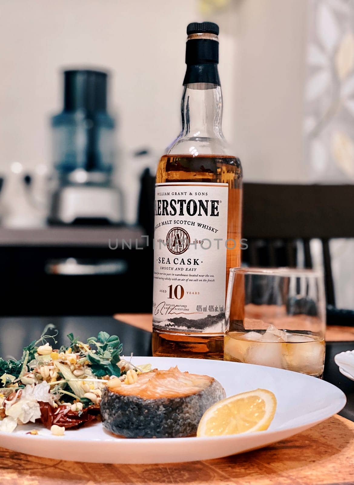 Salmon steak with a salad of herbs, spices and vegetables is served with whiskey. Supper. 07.02.2021. Samara, Russia.