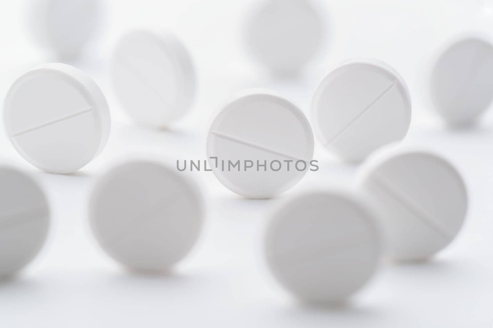 A pile of white pills scattered on a bright white background. Selective focus. Mockup layout, template.