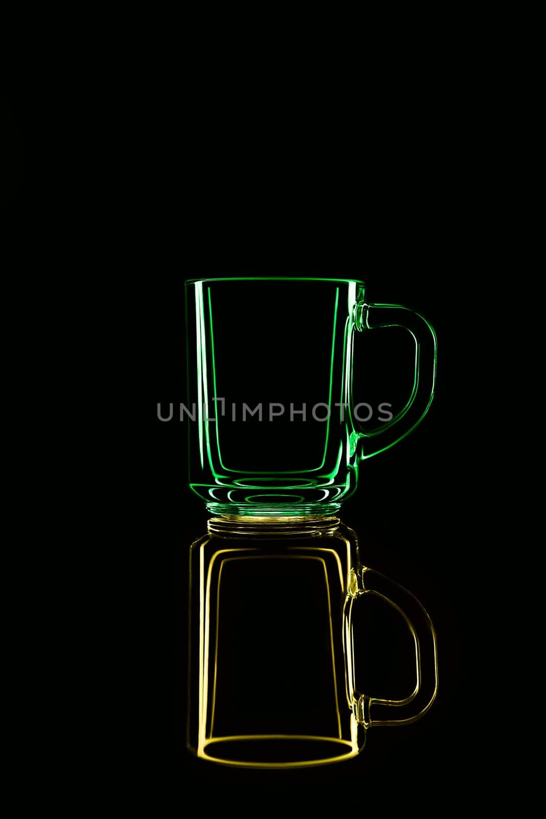 Just a glass on a black background with a reflection. Yellow and green. Isolated.