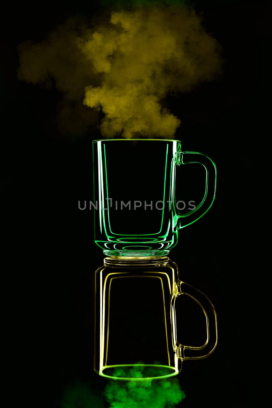 Just a glass on a black background with a reflection. Yellow and green, with steam. Isolated.