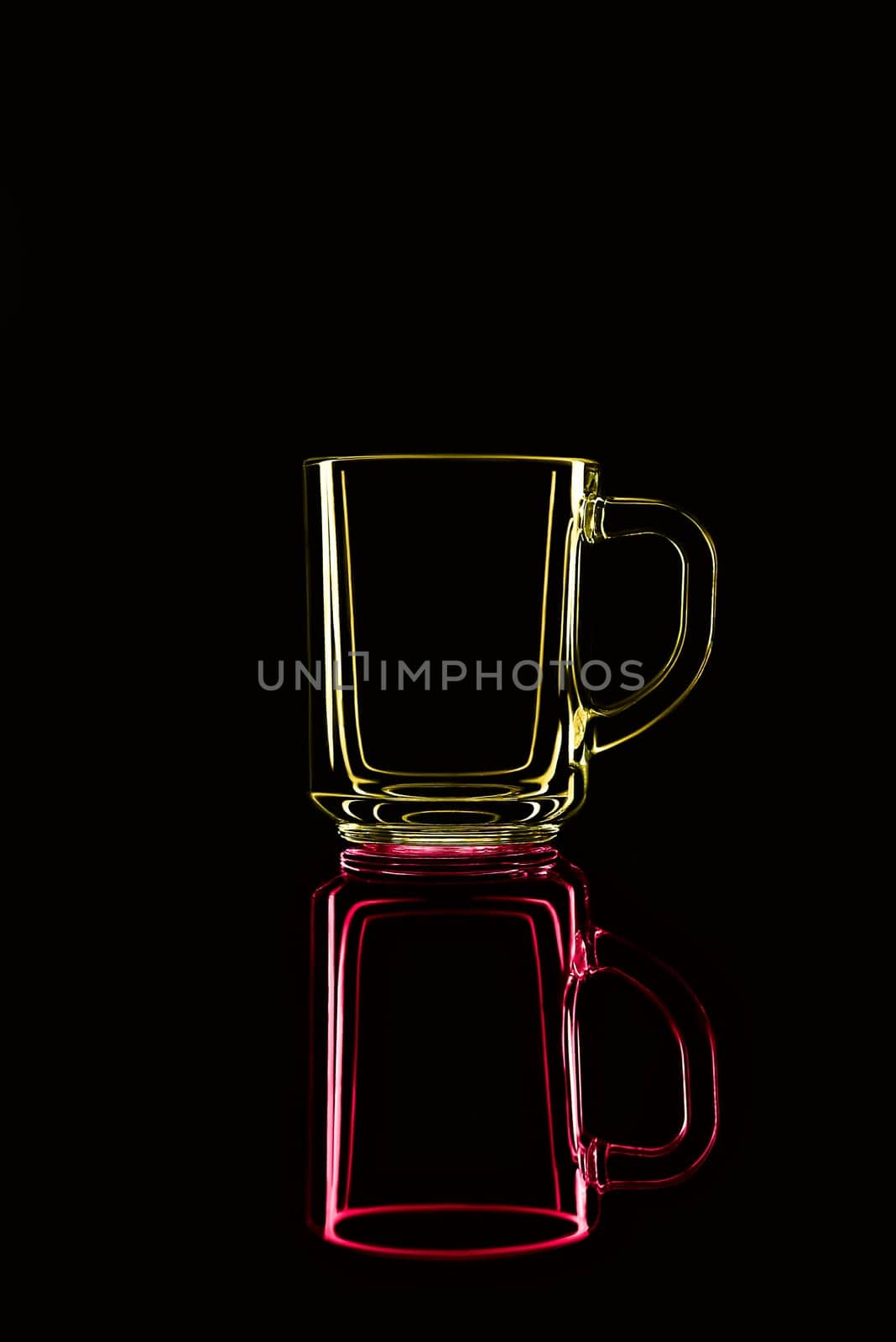 Just a glass on a black background with a reflection. Yellow and red. Isolated.