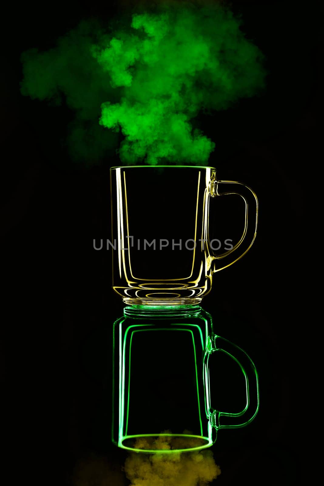 Just a glass on a black background with a reflection. Yellow and green, with steam. Isolated.