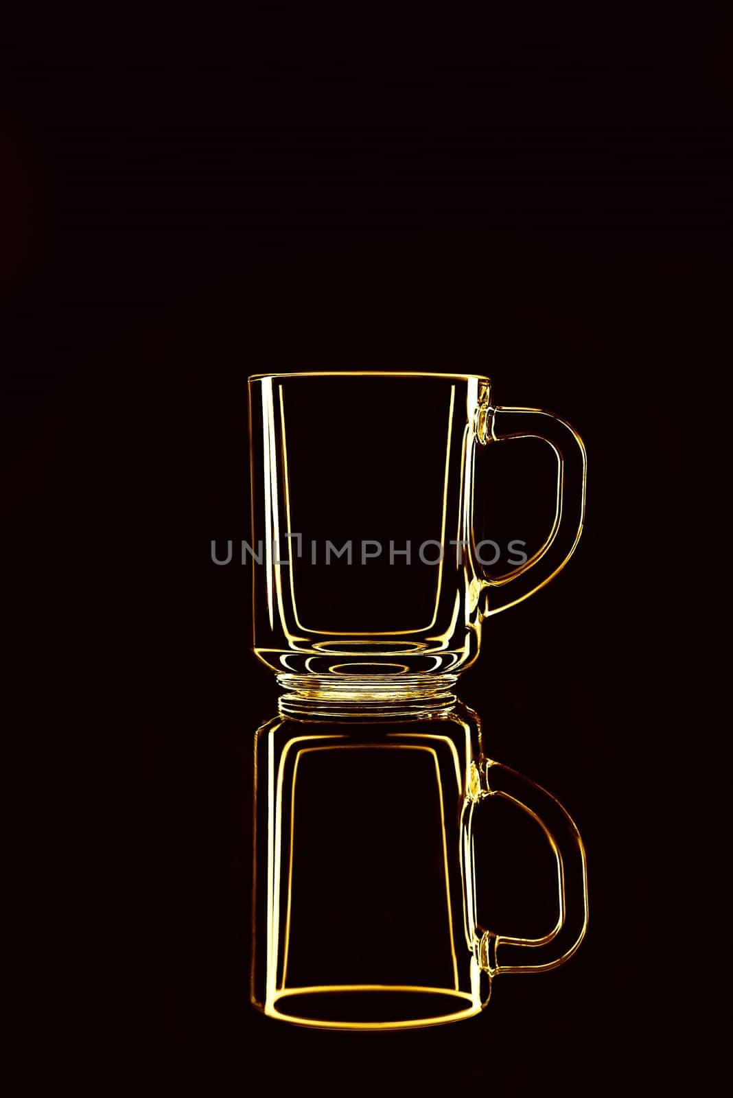 Just a glass on a black background with a reflection. Yellow colors. Isolated.