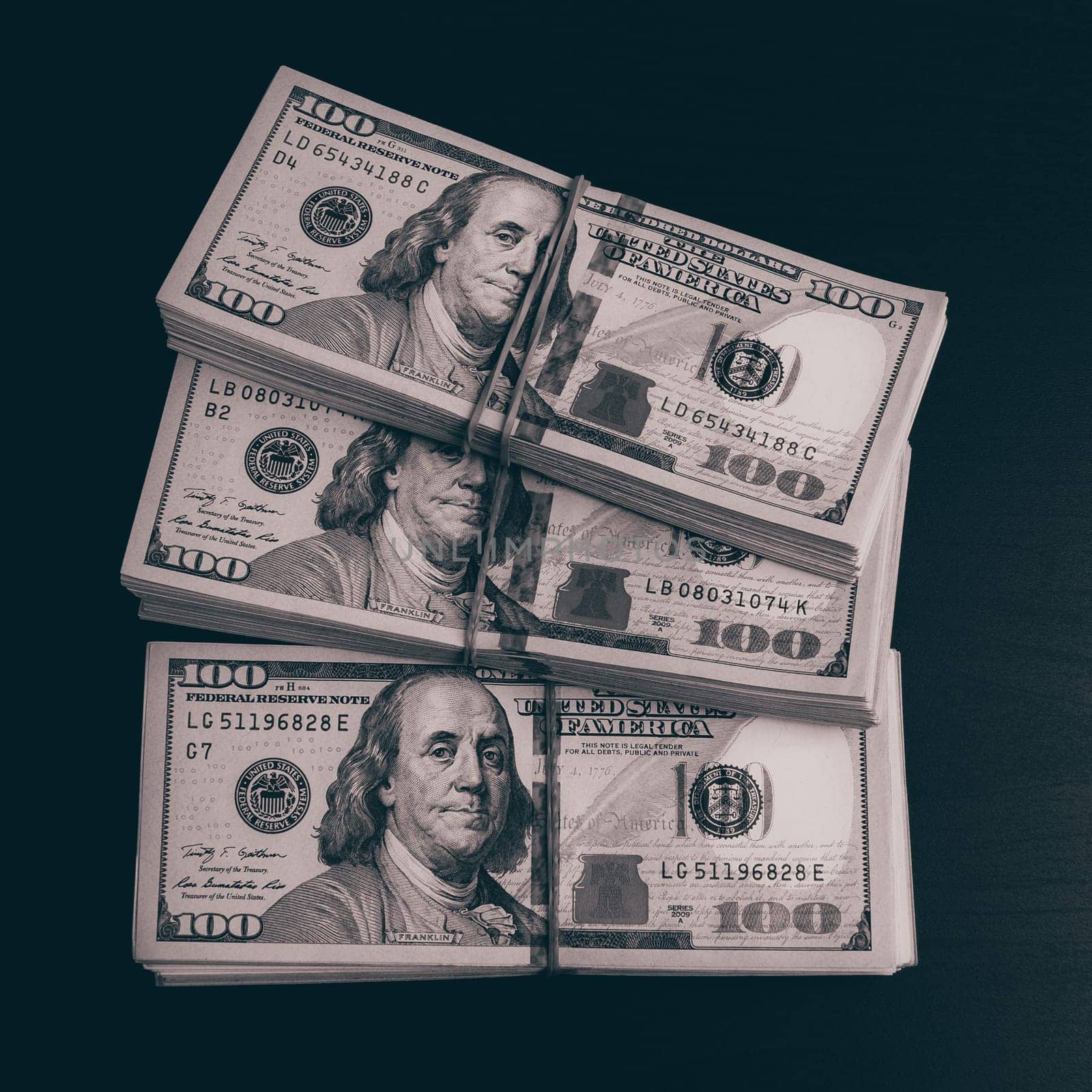 Wads of dollars in cash on a dark table. Three hundred-dollar packs.