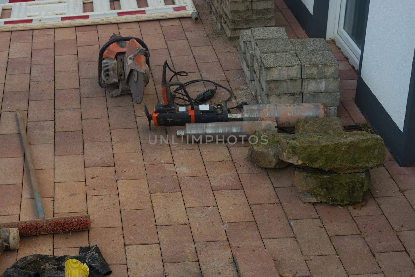 Concrete drilling with industrial boring machine next to it is a stone cutting saw