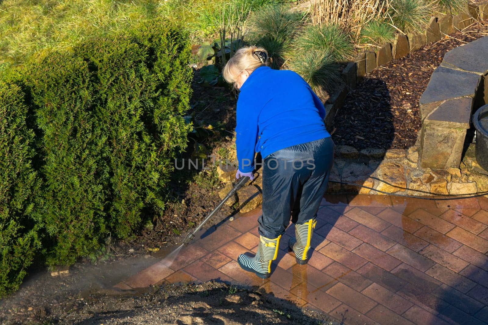 Worker cleaning driveway with gasoline high pressure washer splashing the dirt,professional cleaning services.High pressure cleaning,lower body.