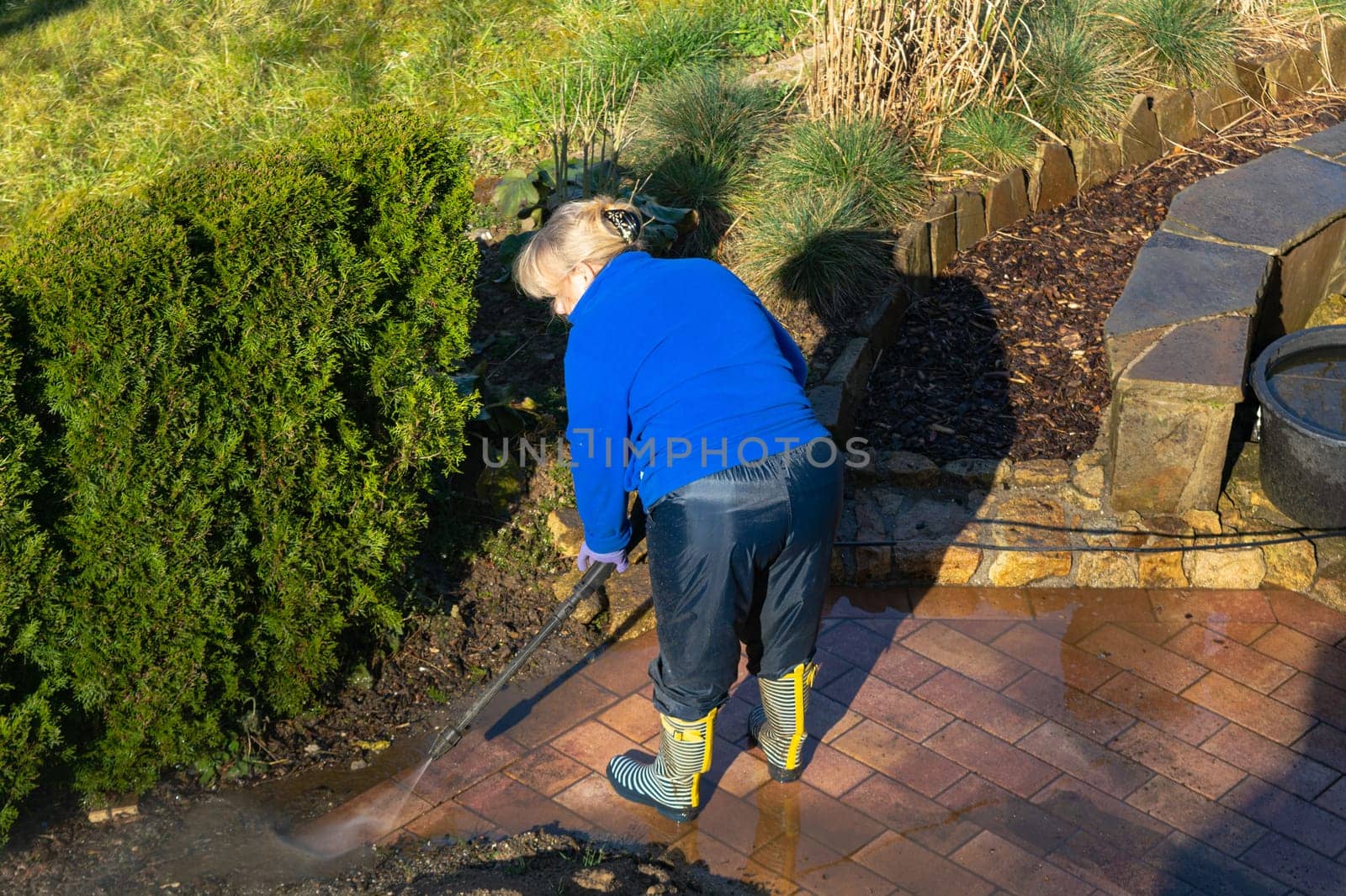 Patio Pressure Cleaning. Caucasian Woman Washing His Concrete Floor Patio Using High Pressured Water Cleaner.