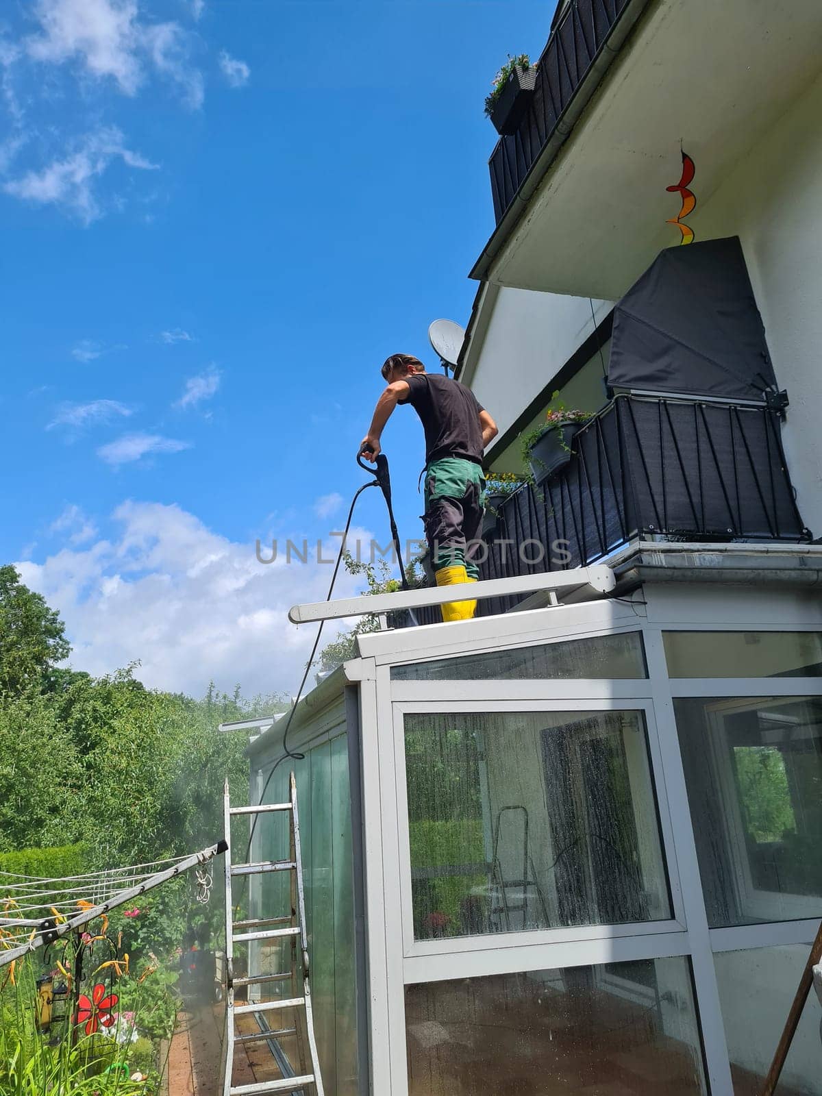 Man power washing conservatory roof and windows