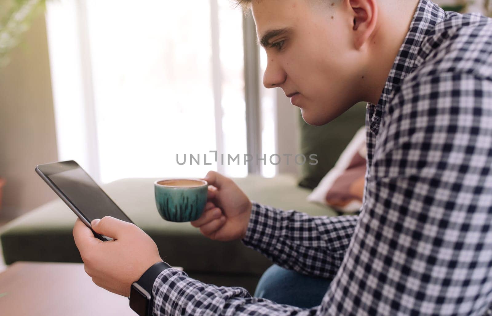 Man holds and reading smartphone with black screen and coffee cup. Blurred background. High quality photo