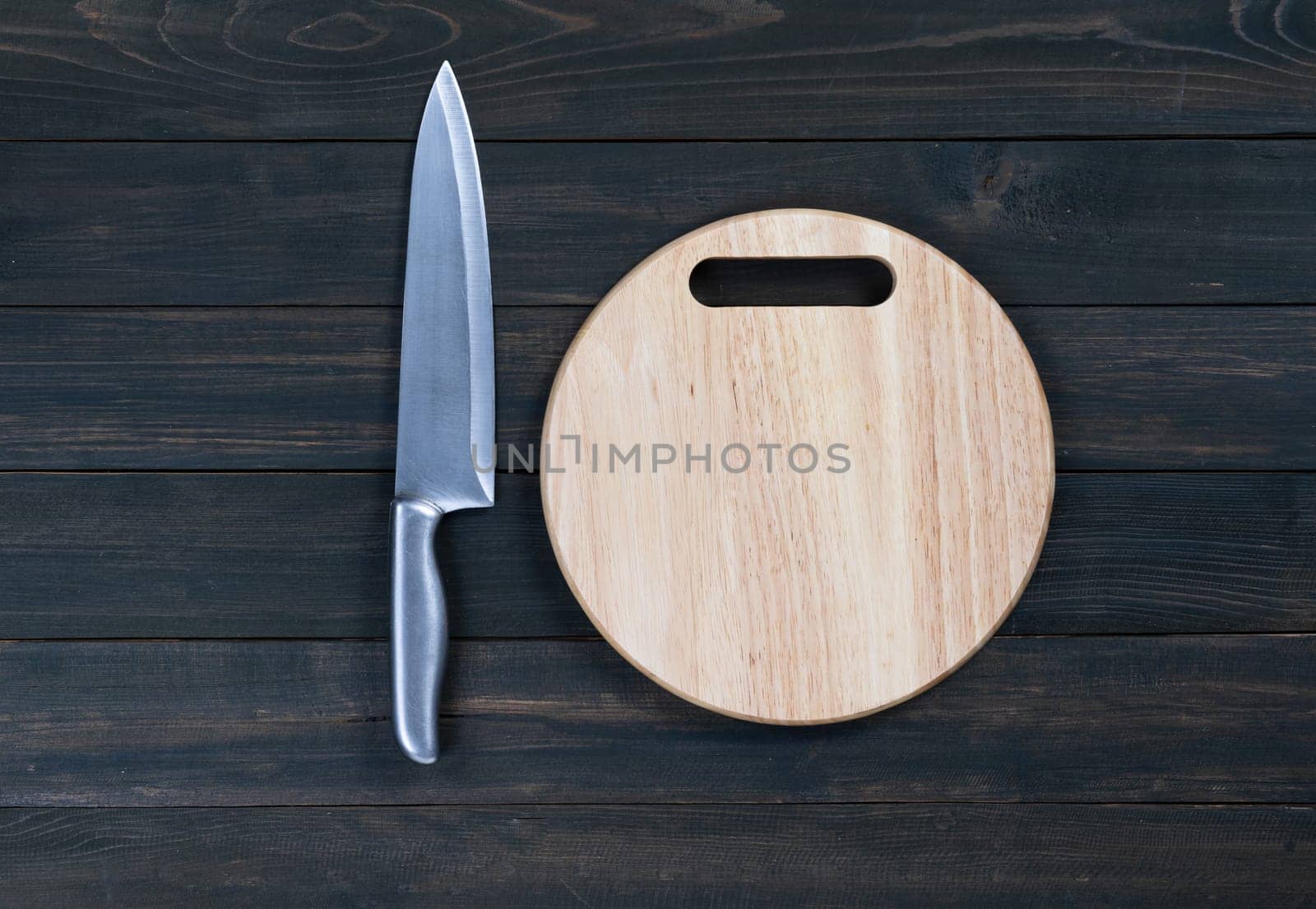kitchen knife and wooden round empty cutting board on a wooden table close up