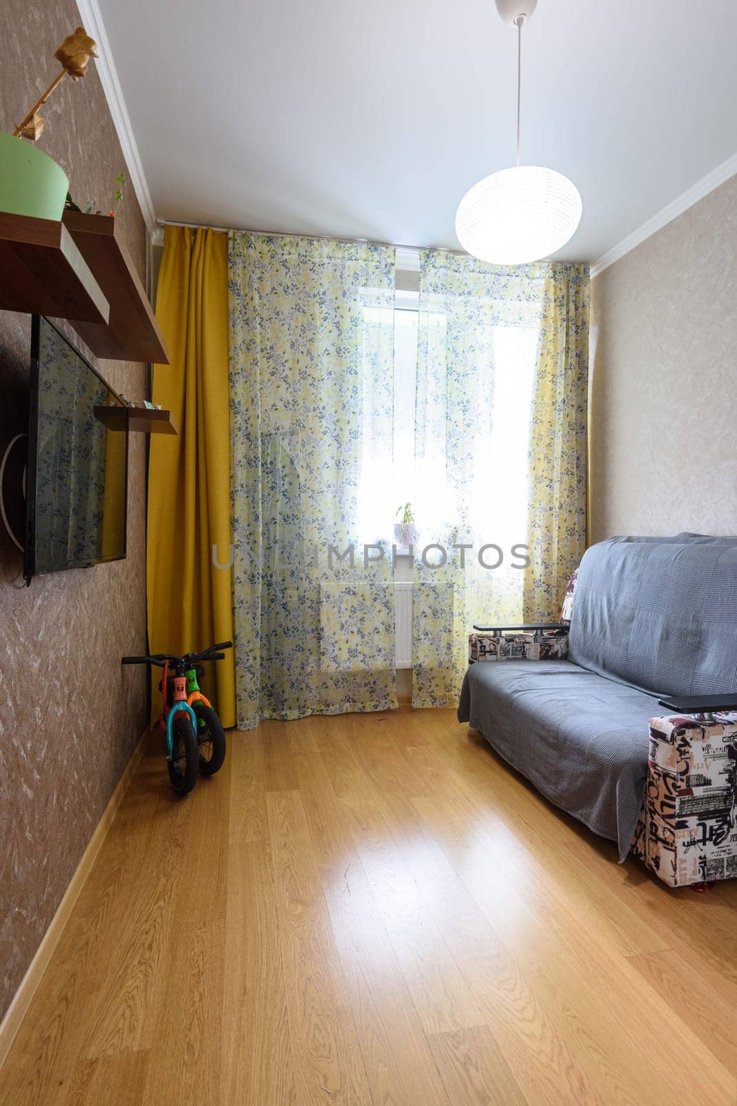 Anapa, Russia - March 1, 2021: Interior of a small modest room with a sofa and a TV on the wall