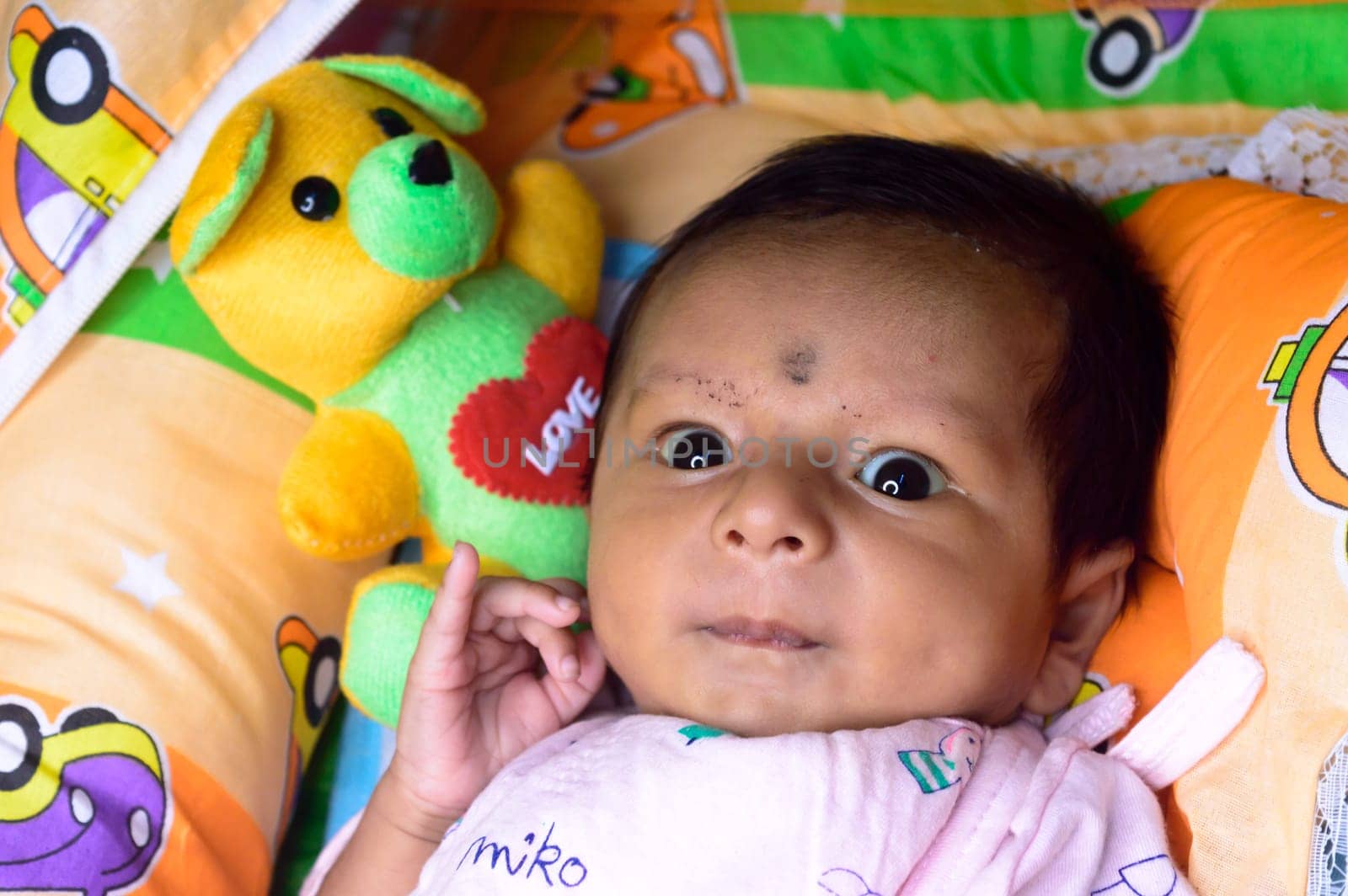 Close up portrait of cute Sweet infant toddler feeling wonder and amazed about surrounding environment. Beautiful Newborn Baby looking something unfamiliar and remarkable astonishingly. Indian ethnicity. High angel Front view.