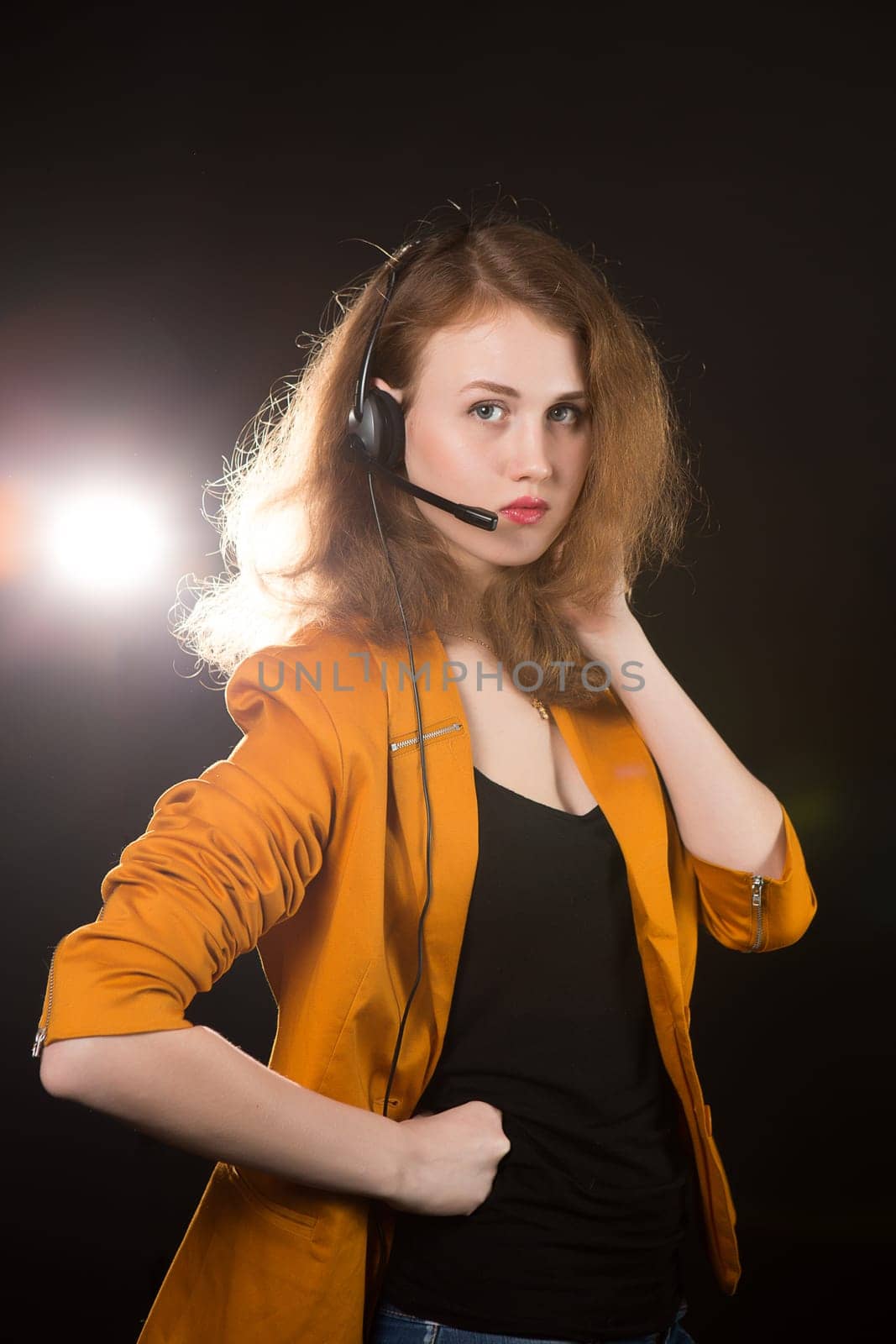 Young beautiful woman-operator with headphone smiles, it is isolated on black background.