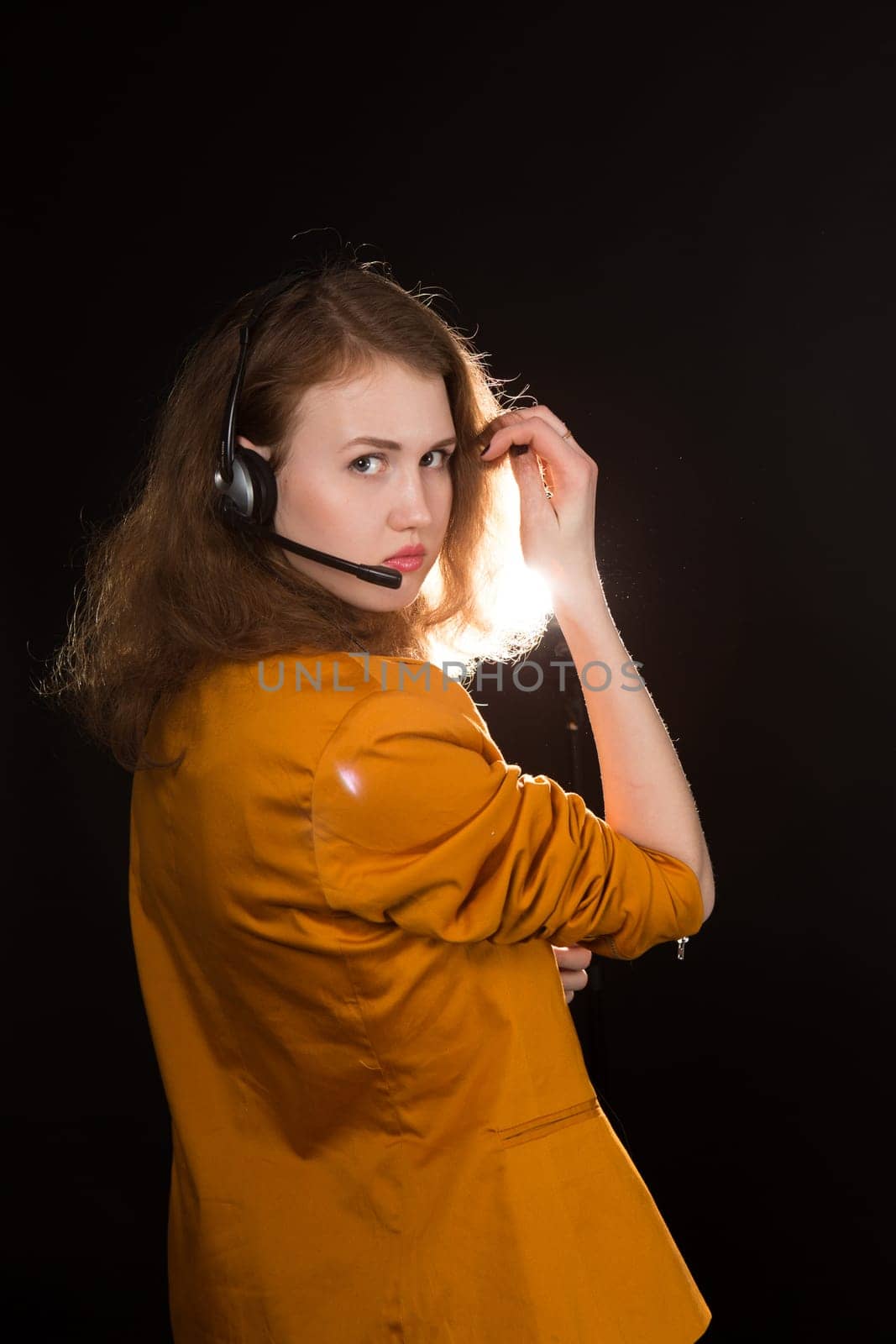 Young beautiful woman-operator with headphone smiles, it is isolated on black background.