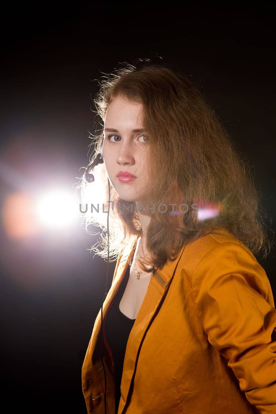 Young beautiful woman-operator with headphone smiles, it is isolated on black background.