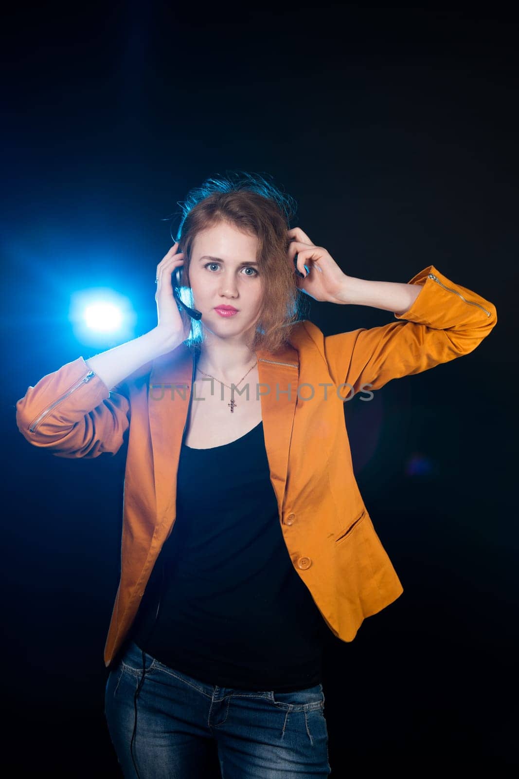 Young beautiful woman-operator with headphone smiles, it is isolated on black background.