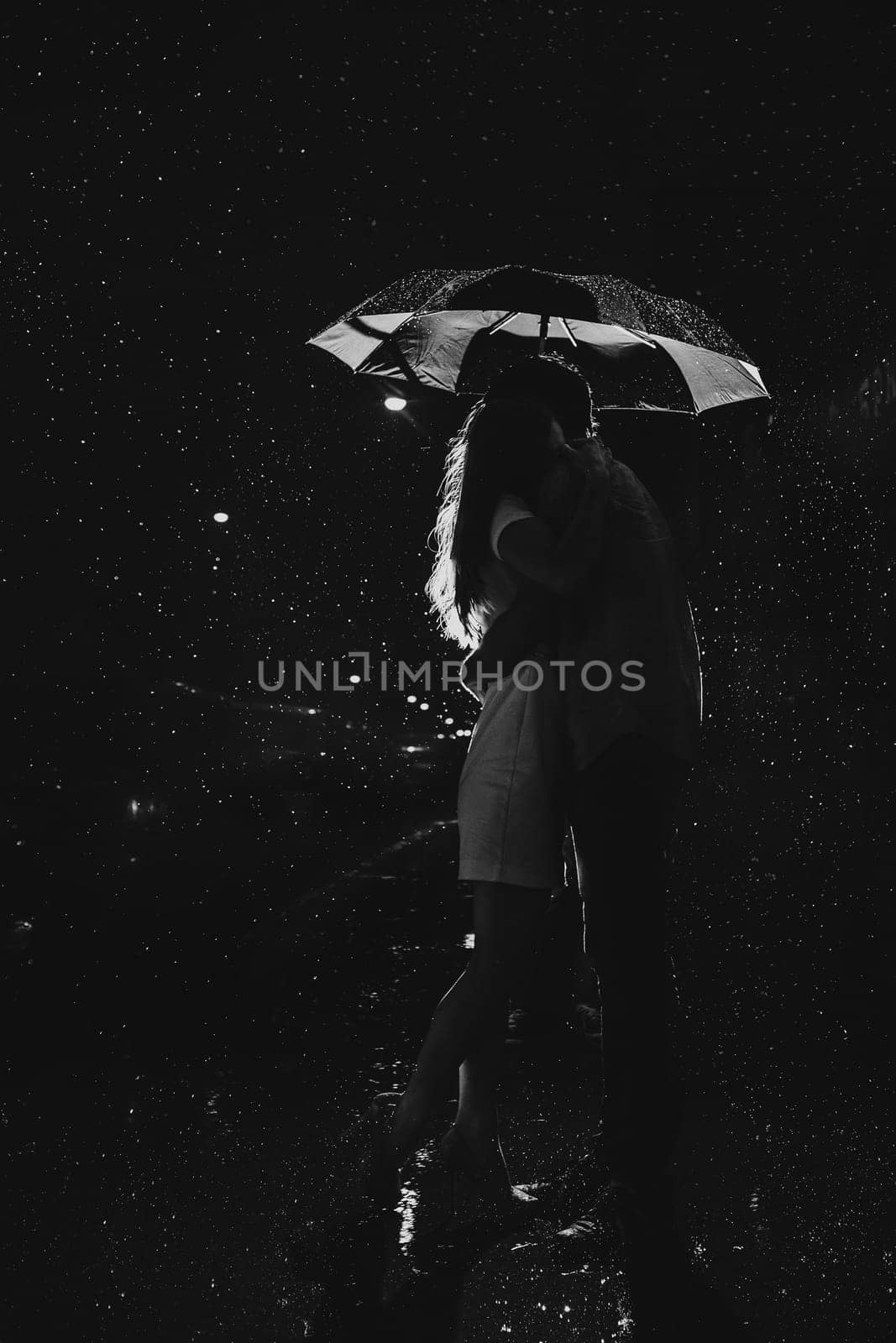 Love in the rain / Silhouette of kissing couple under umbrella