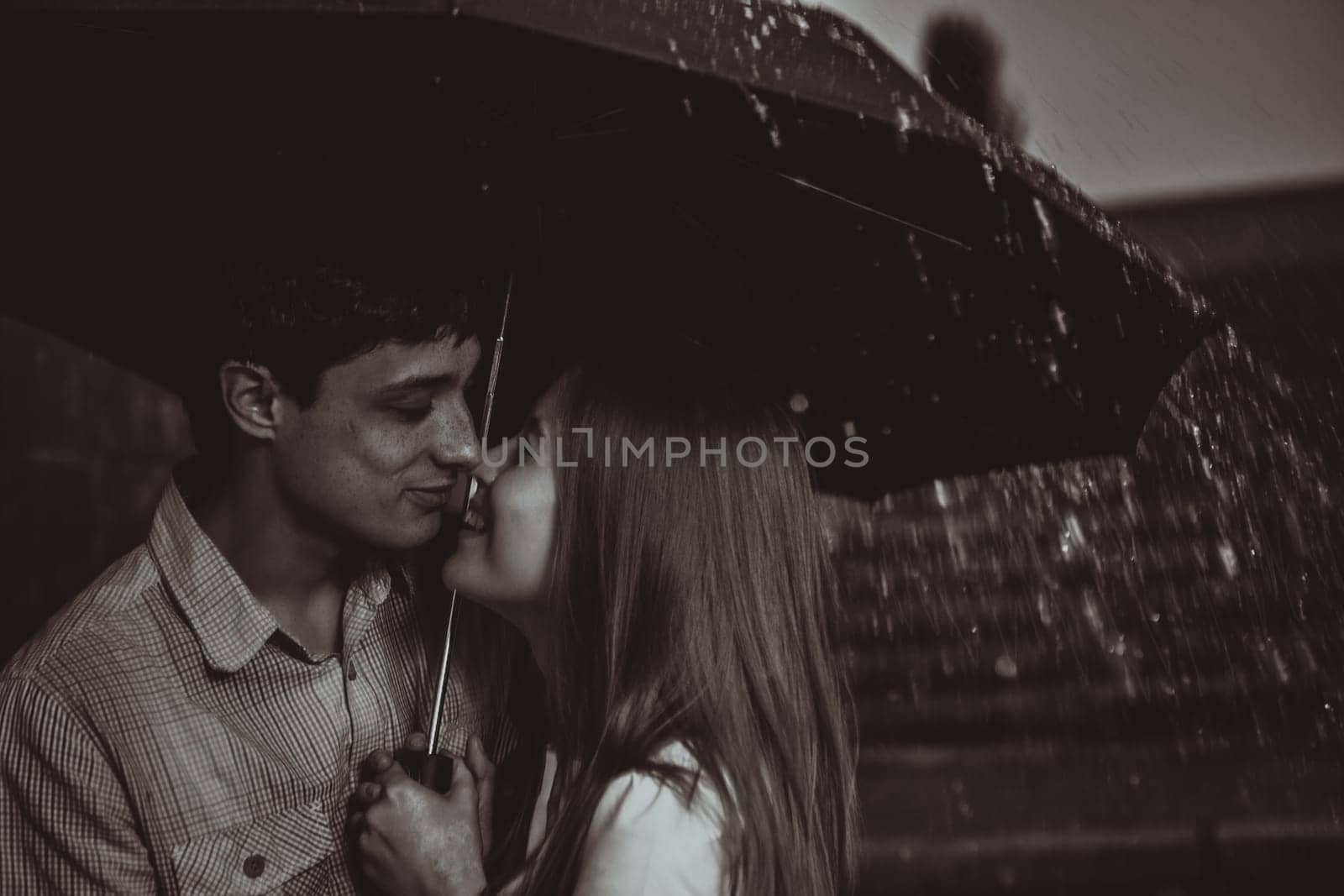 Love in the rain / Silhouette of kissing couple under umbrella