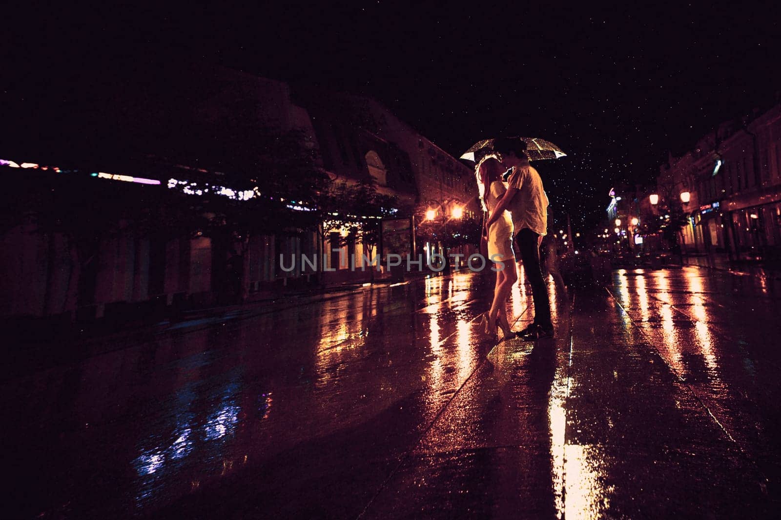 Love in the rain / Silhouette of kissing couple under umbrella