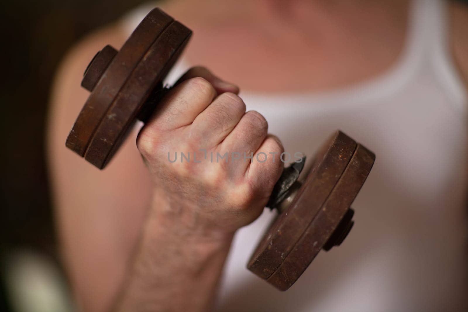 fist with iron dumbbell, man does physical exercises with dumbbells close-up, shallow depth of field