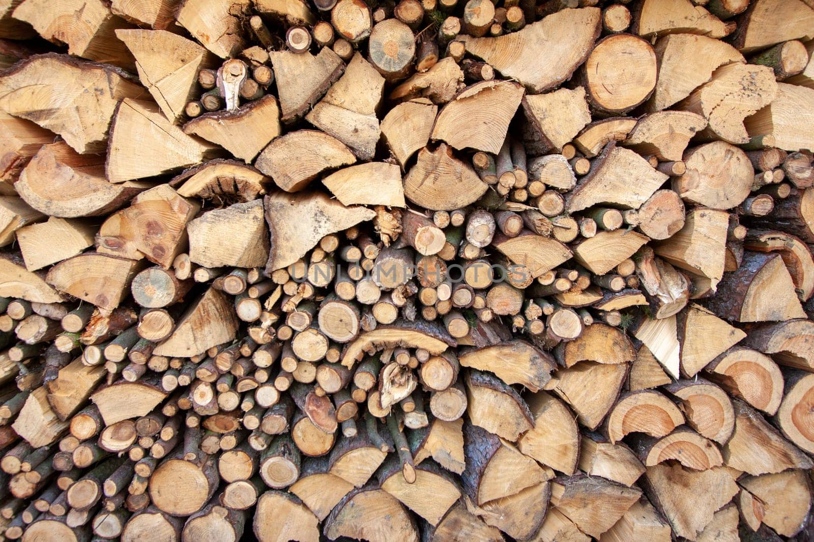 Natural wooden background - detailed chopped firewood. Wood stacked and ready for winter pile of wooden logs.
