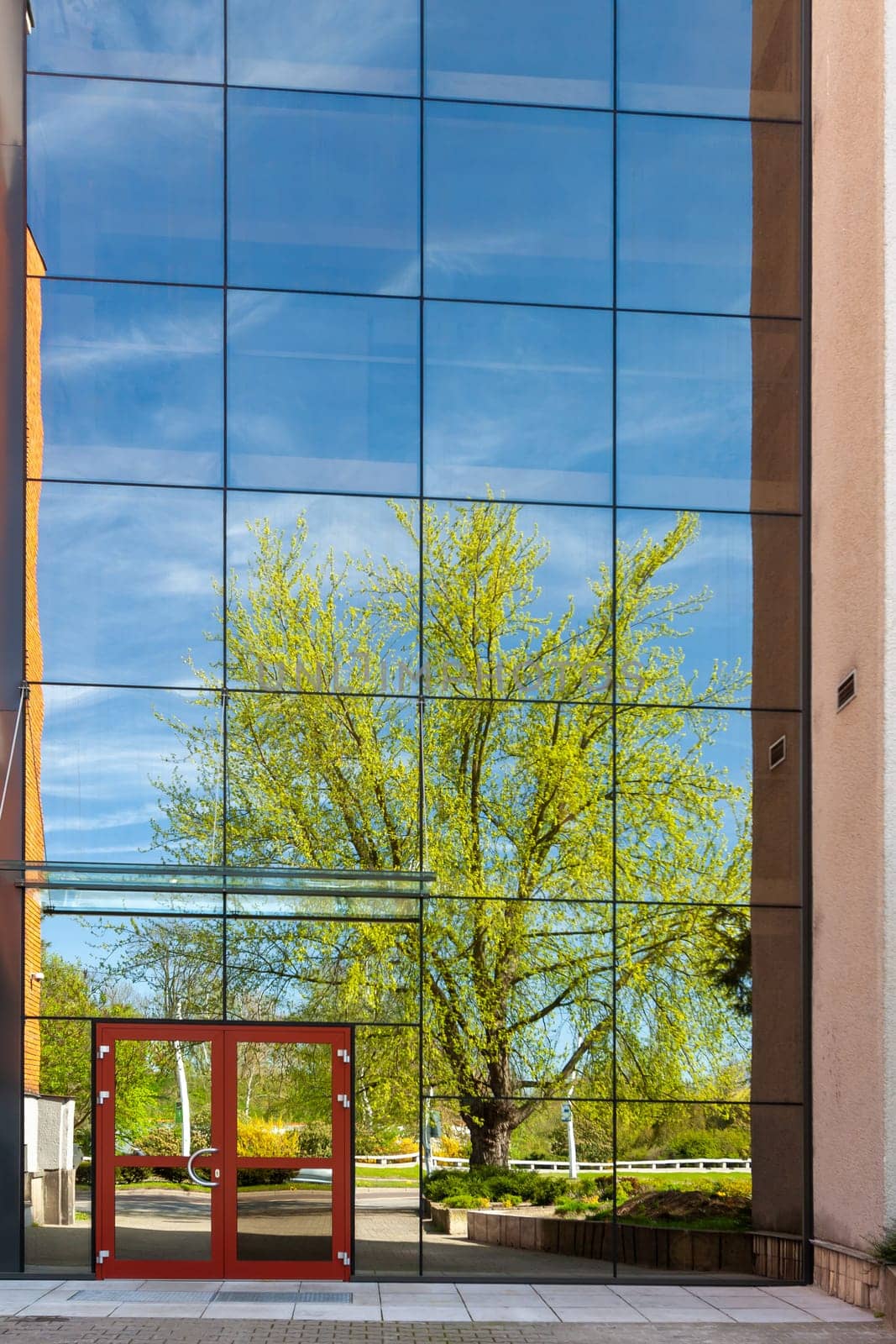 A modern office building with glass doors and windows, reflection in the glass of a city park Pardubice. Czech Republic
