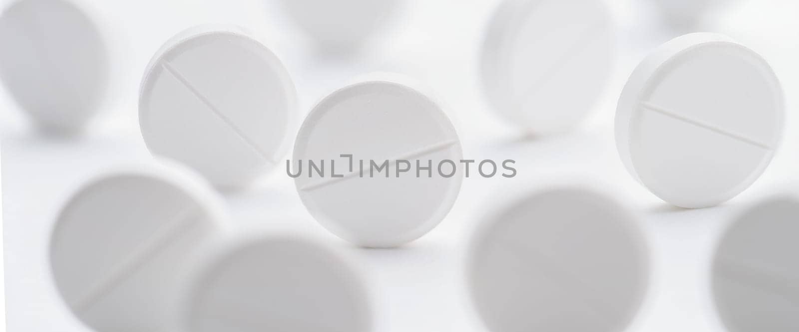 A pile of white pills scattered on a bright white background. Selective focus. Mockup layout, template.