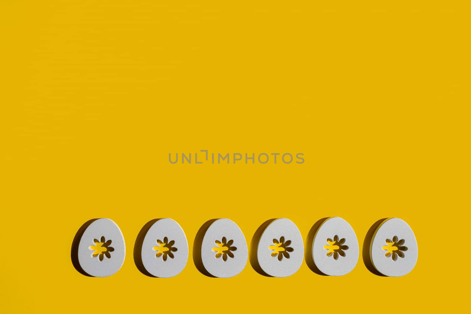 Some decorated wooden Easter eggs on a yellow surface