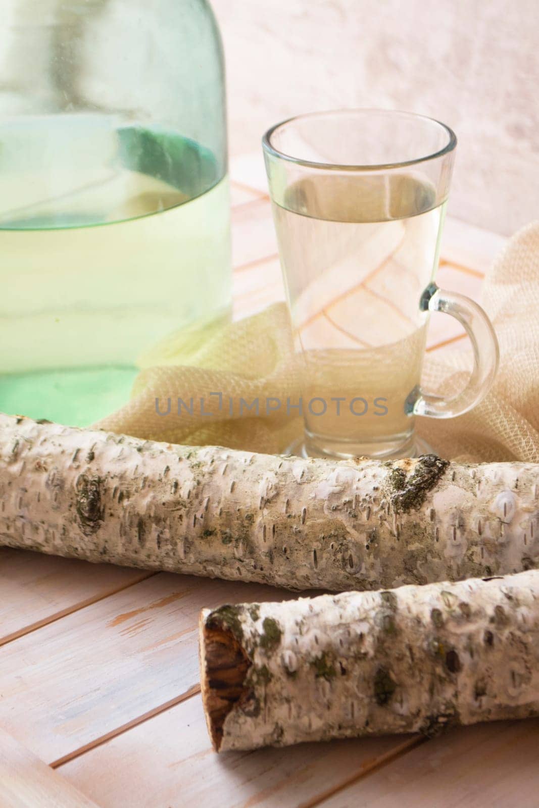 Birch sap juice in a glass mug with a birch stump, vertical image