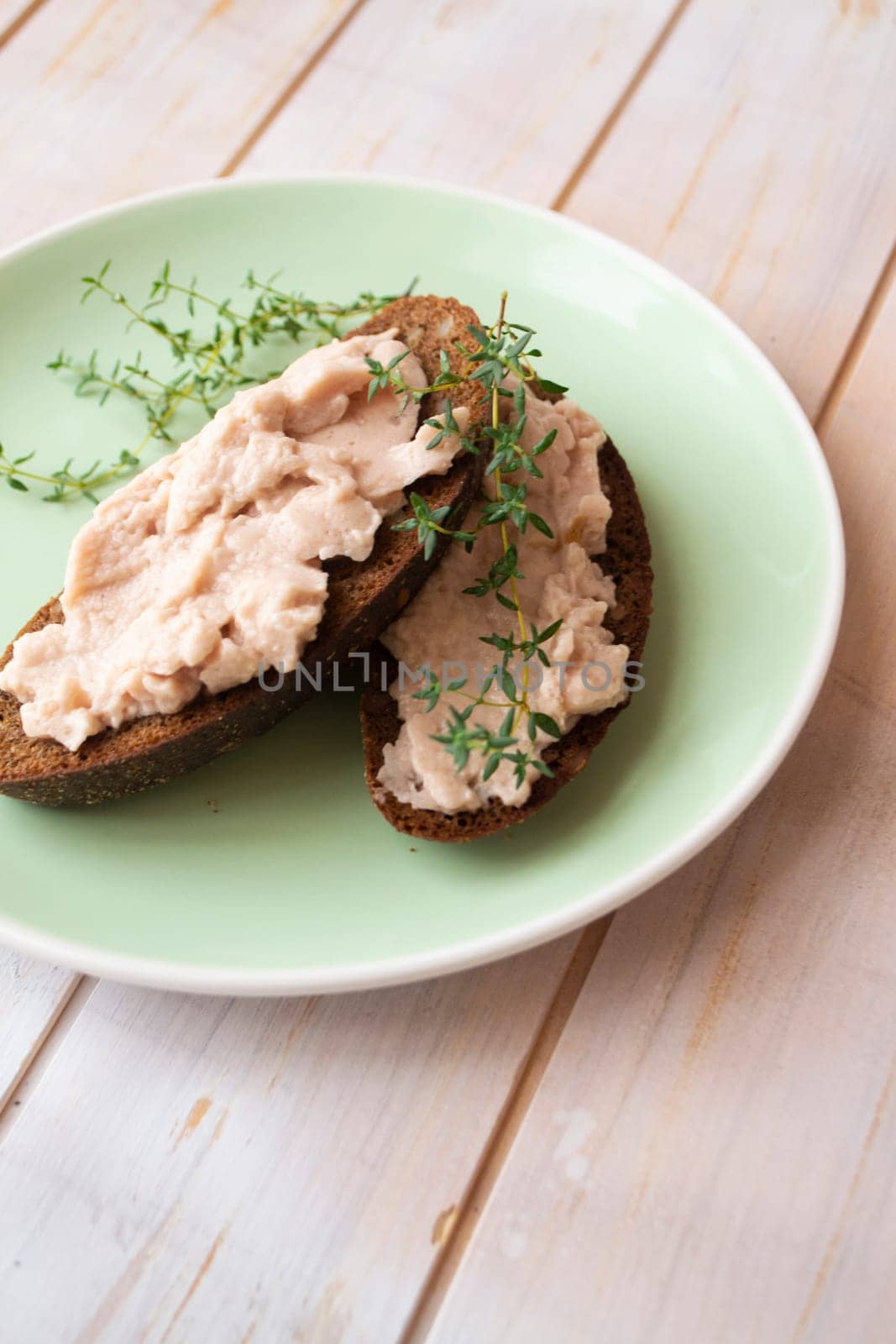 Homemade meat snack chicken liver pate with savory and olives on slices of dark bread. Vertical image