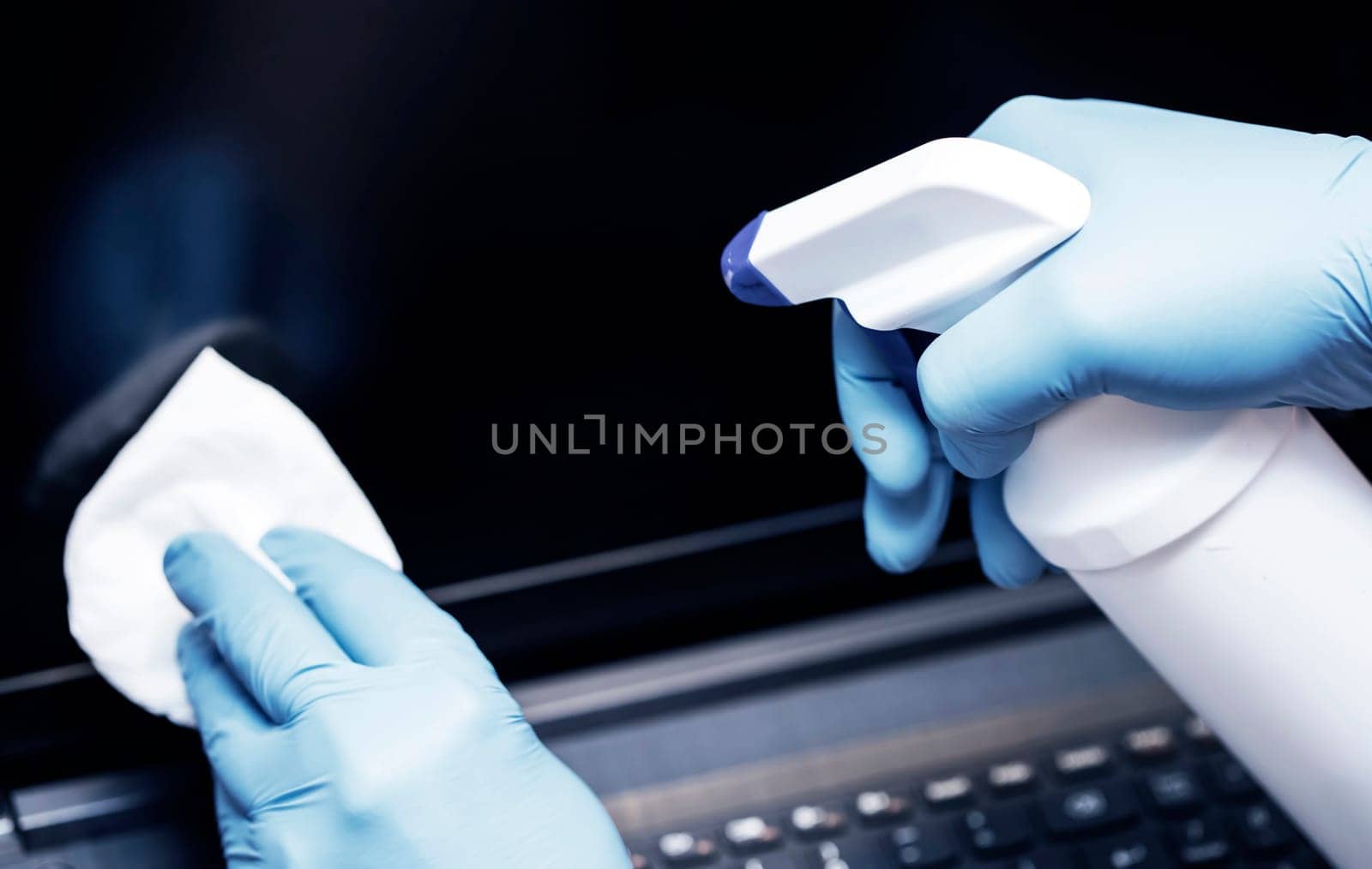 Coronavirus COVID-19 sanitize cleaning disinfection of work desk.Office sanitizing wipe wiping laptop with disinfecting wipes.