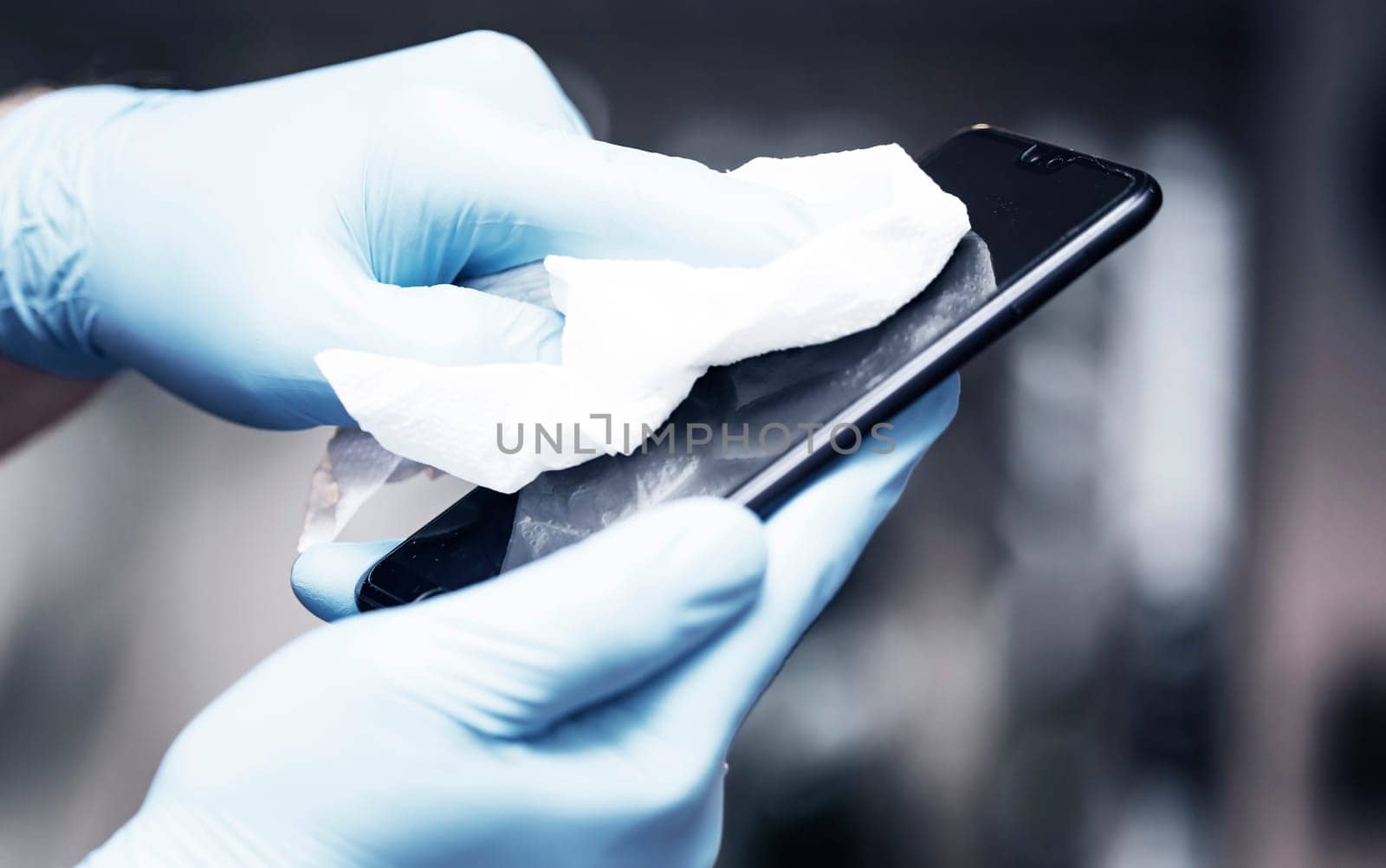 Coronavirus COVID-19 sanitize cleaning disinfection of smartphone.Office sanitizing wipe wiping phone with disinfecting wipes.