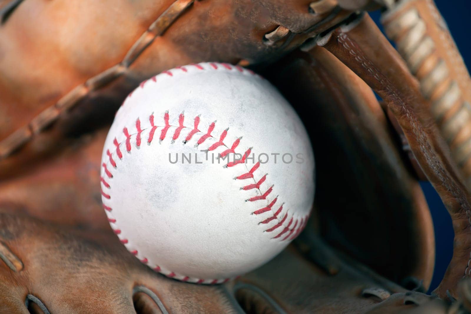 Close up image of an old used baseball and baseball glove.