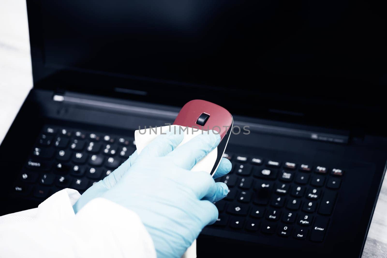 Office sanitizing wiping mouse with disinfectant. Coronavirus COVID-19 sanitize cleaning, disinfection of work desk.